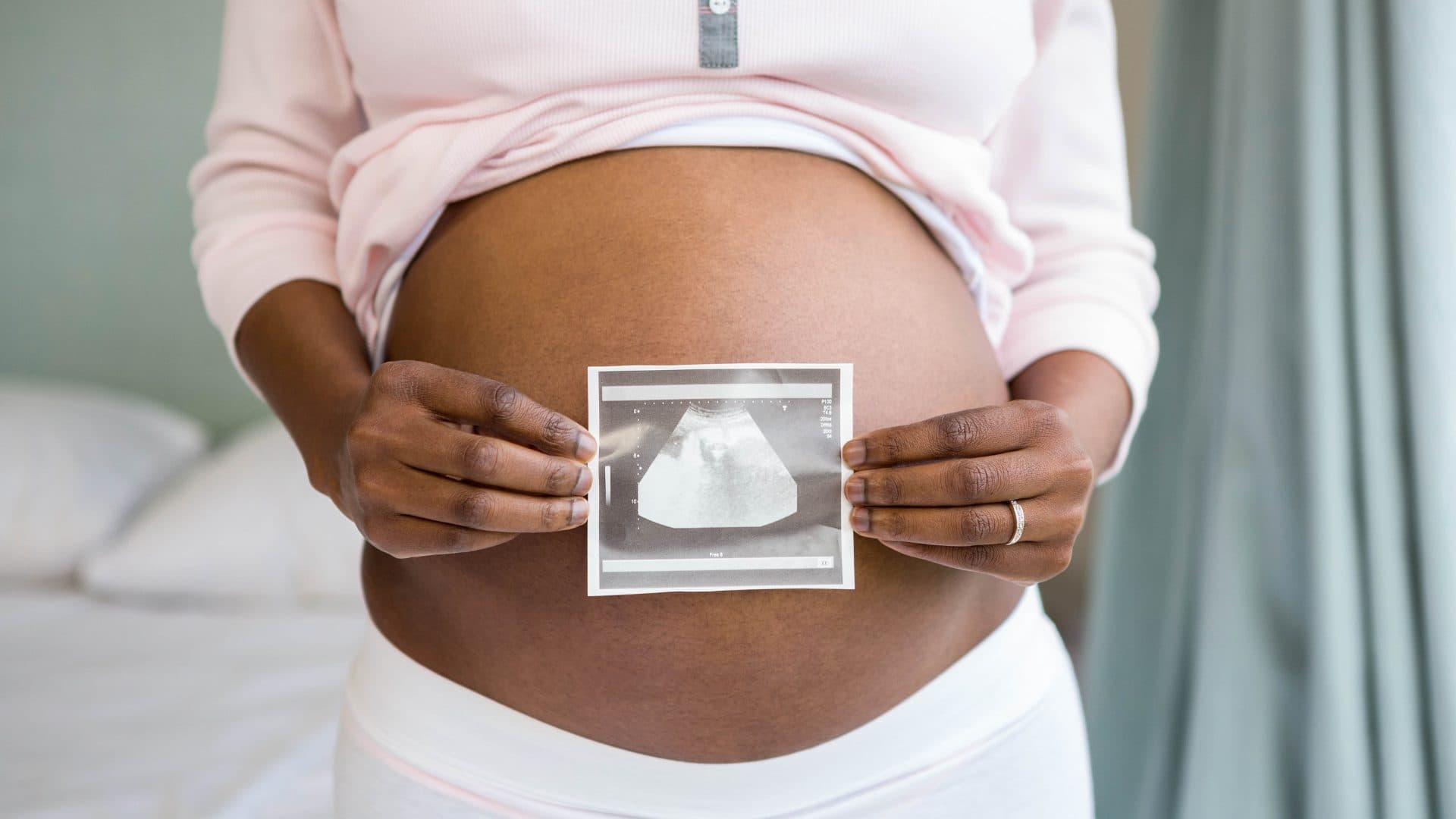 A pregnant woman holding an ultrasound print