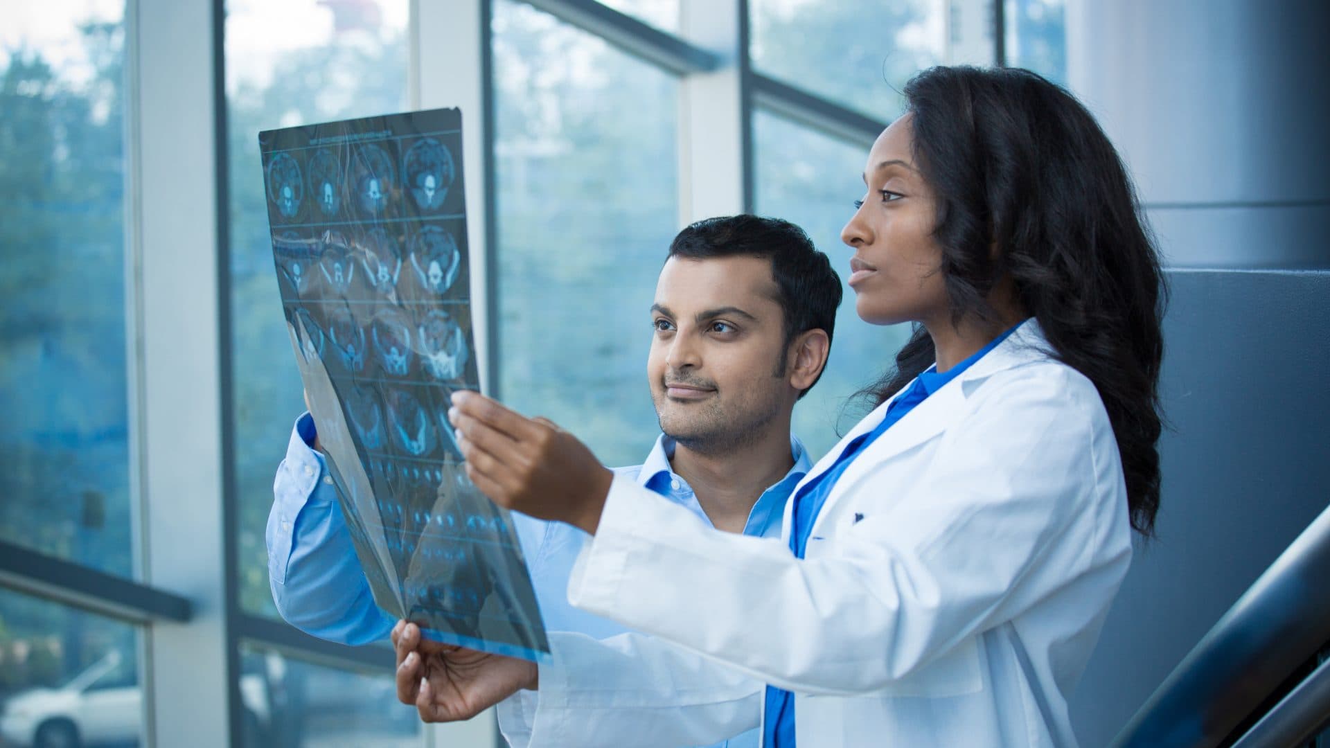 Two clinicians reviewing an imaging film together by a window
